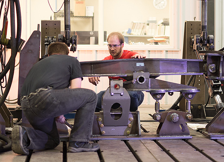 Two men setting up a part in a testing machine