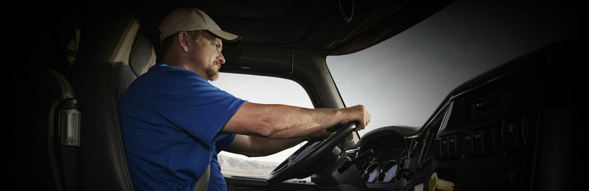 Low shot of a truck driver with his hands on the steering wheel looking out the windshield