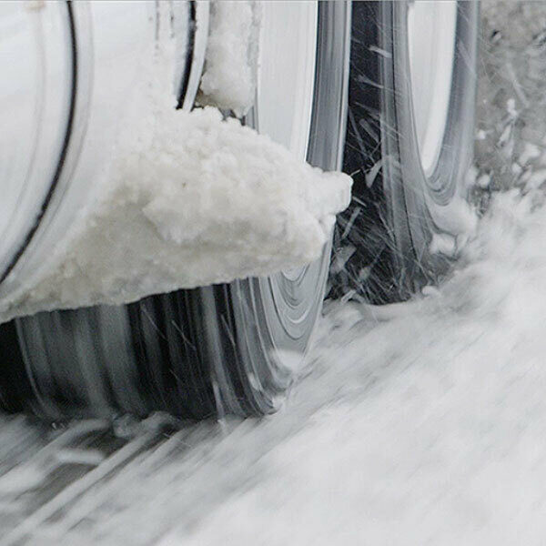 A close up of semi truck tires in a 6x2 configuration on a snowy road