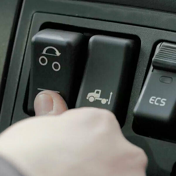 A finger pressing a button to lower a 6x2 lift axle