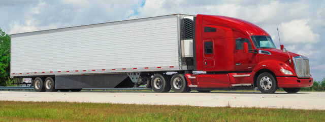 Red semi truck hauling an enclosed trailer on a highway