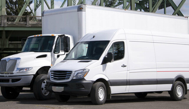 A white box truck behind a white cargo van