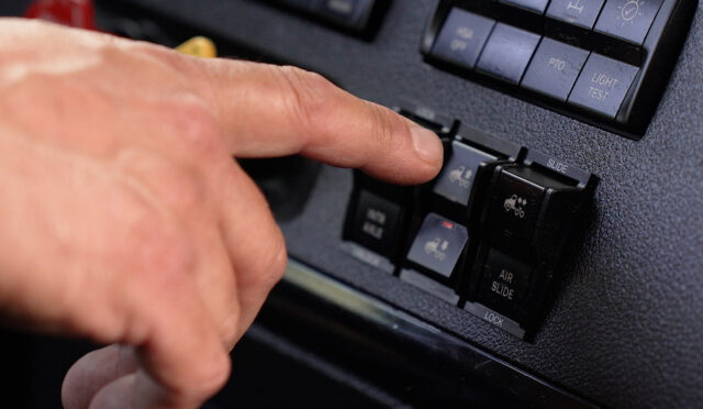 Hand pressing SmartValve raise button on truck dashboard